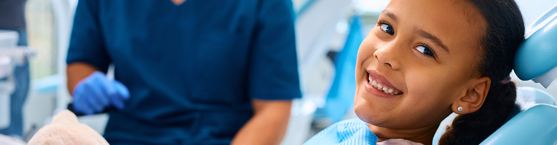 Dentist behind smiling child in dentist chair.